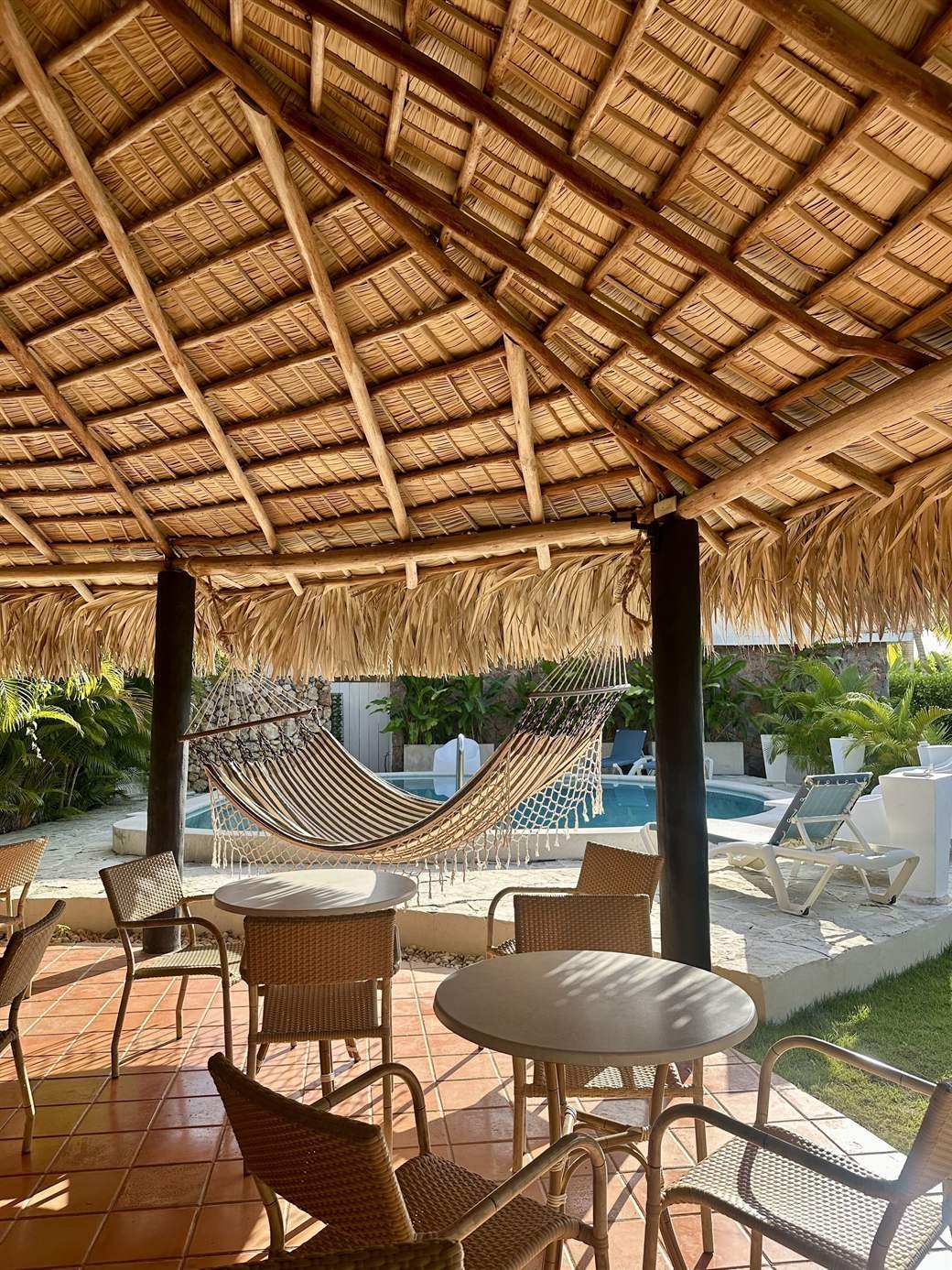 El Rincón de Abi: covered breakfast area with wicker chairs and a hammock next to the pool