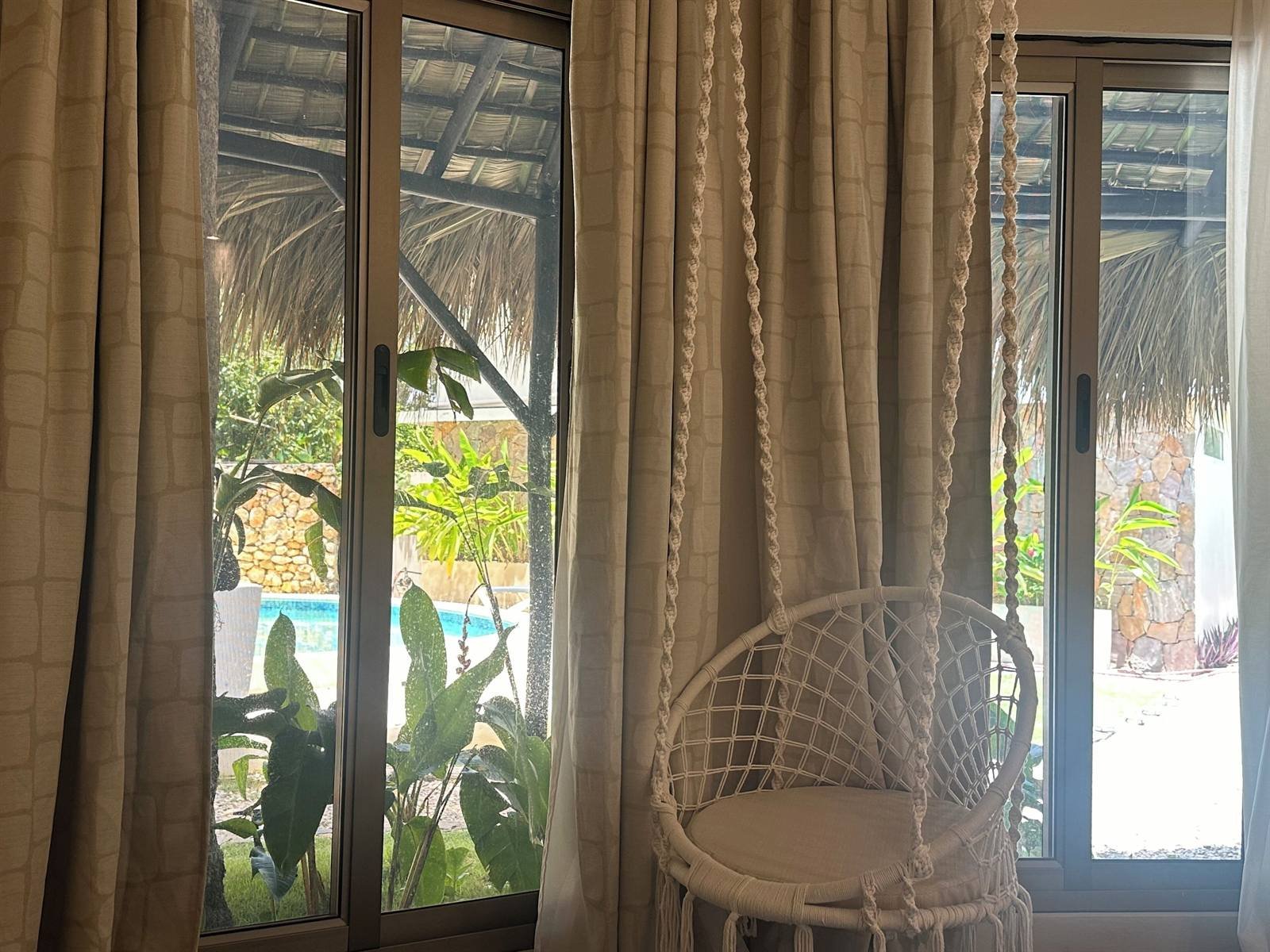 El Rincón de Abi: macramé hanging chair by a glass door looking onto the pool